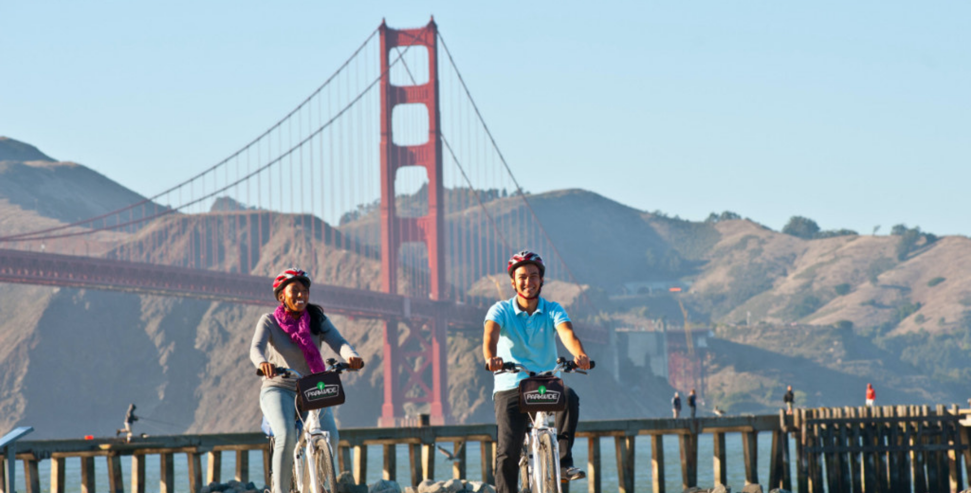 couple biking along the sf waterfront near the golden gate bridge