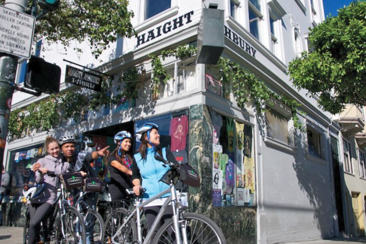 a group of people with bike rentals walking down a street next to a bicycle